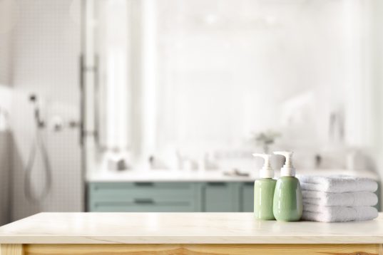 Hotel-Badezimmer: 8 Tipps für ein modernes Design und Wohlfühlambiente 28 Ceramic shampoo, soap bottle and towels on counter over bathroom background. table top and copy space