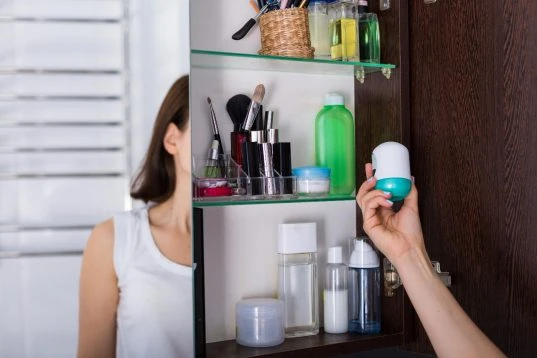 Frau nimmt etwas aus einem Spiegelschrank