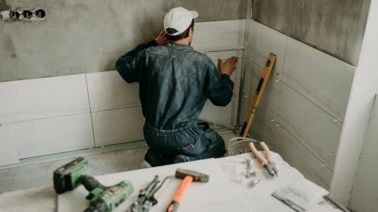 Handwerker verlegt neue Fliesen Handwerker verlegt neue Fliesen