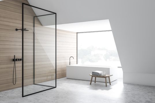 Ecke eines stilvollen Badezimmers mit weißen und hölzernen Wänden, Betonboden, eckiger Badewanne und vertikaler Duschkabine mit Glaswänden. 3D-Rendering